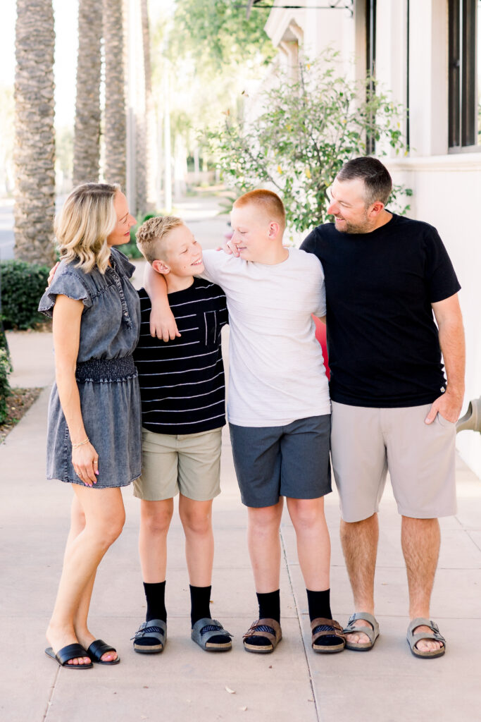 Family of four looks at each other at photography session in Verrado, AZ.