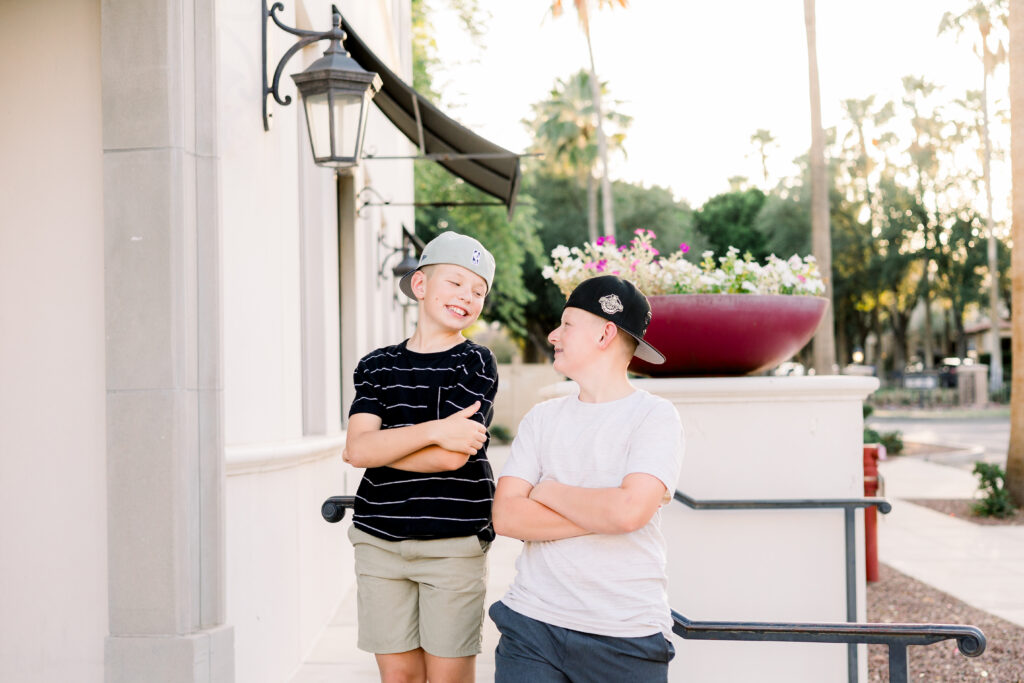 Brothers in backwards hats smile at each other at a photography session.