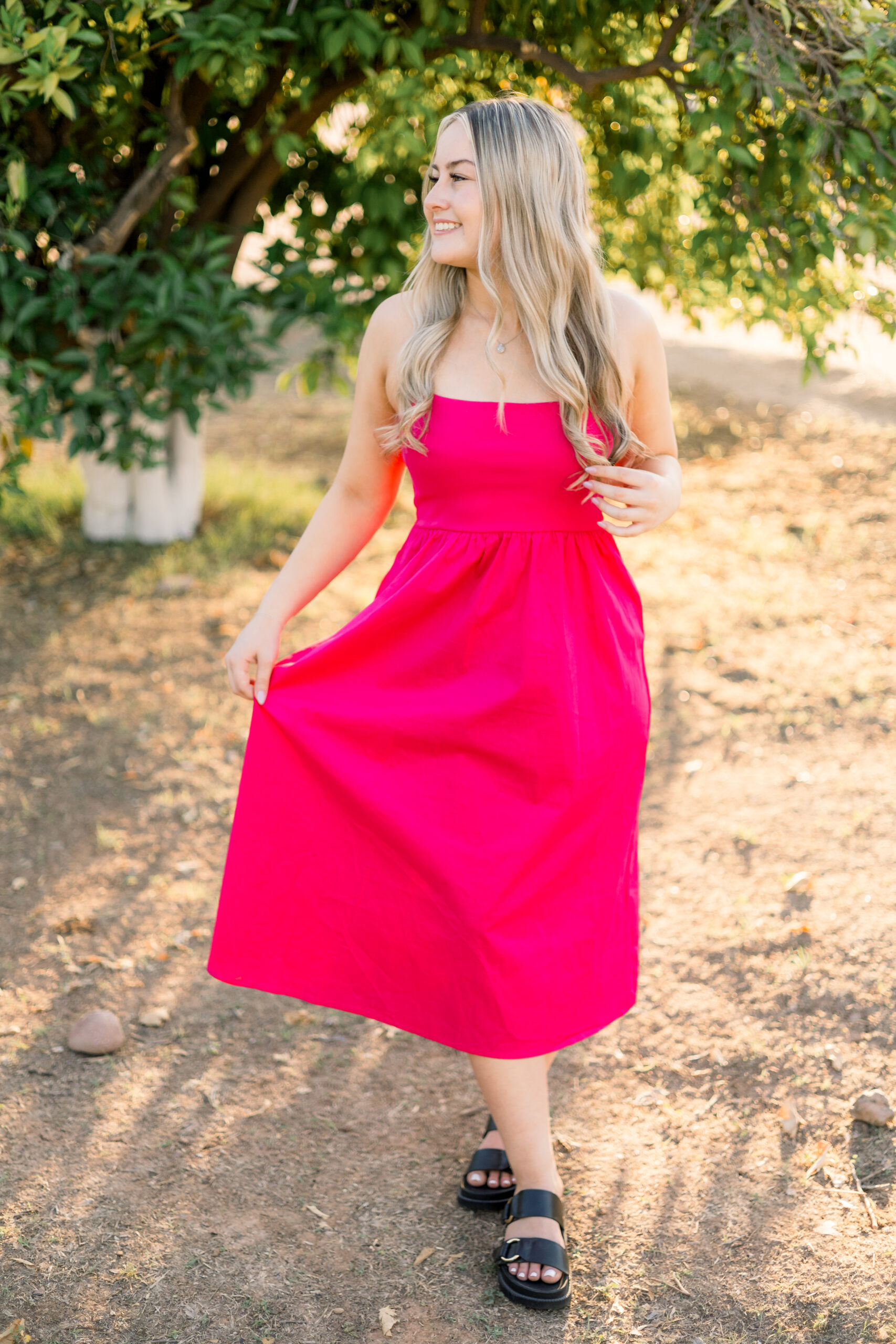 Senior in pink dress looks off camera.