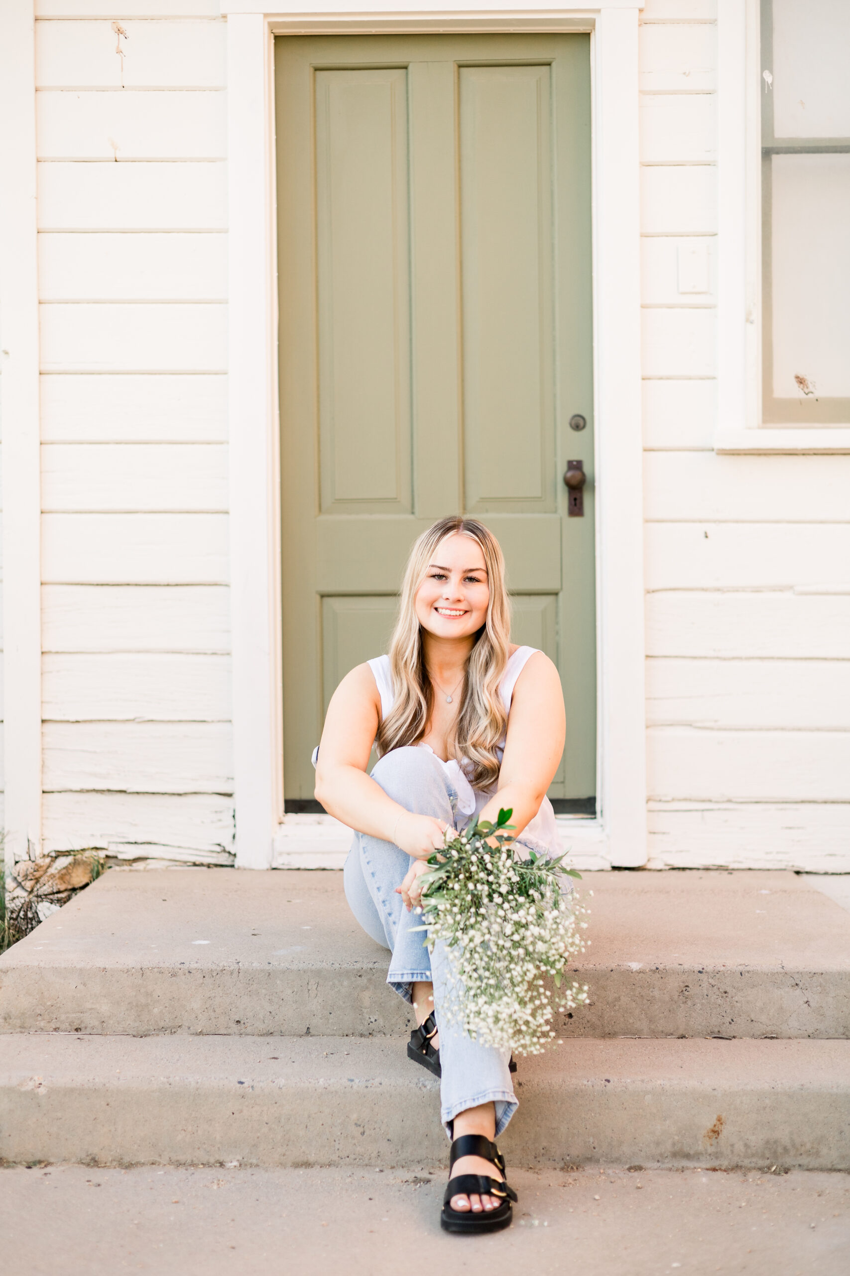 Senior sits on steps of historic building at Sahuaro Ranch Park at senior session.